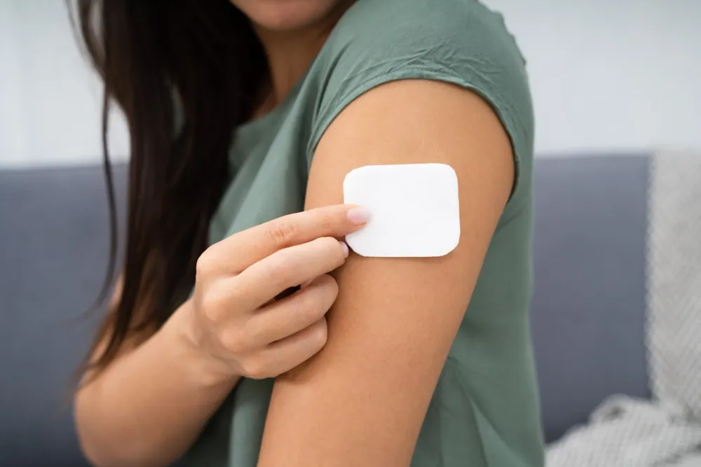 Woman applying Ozempatches transdermal patch to upper arm — daily wellness routine demonstration